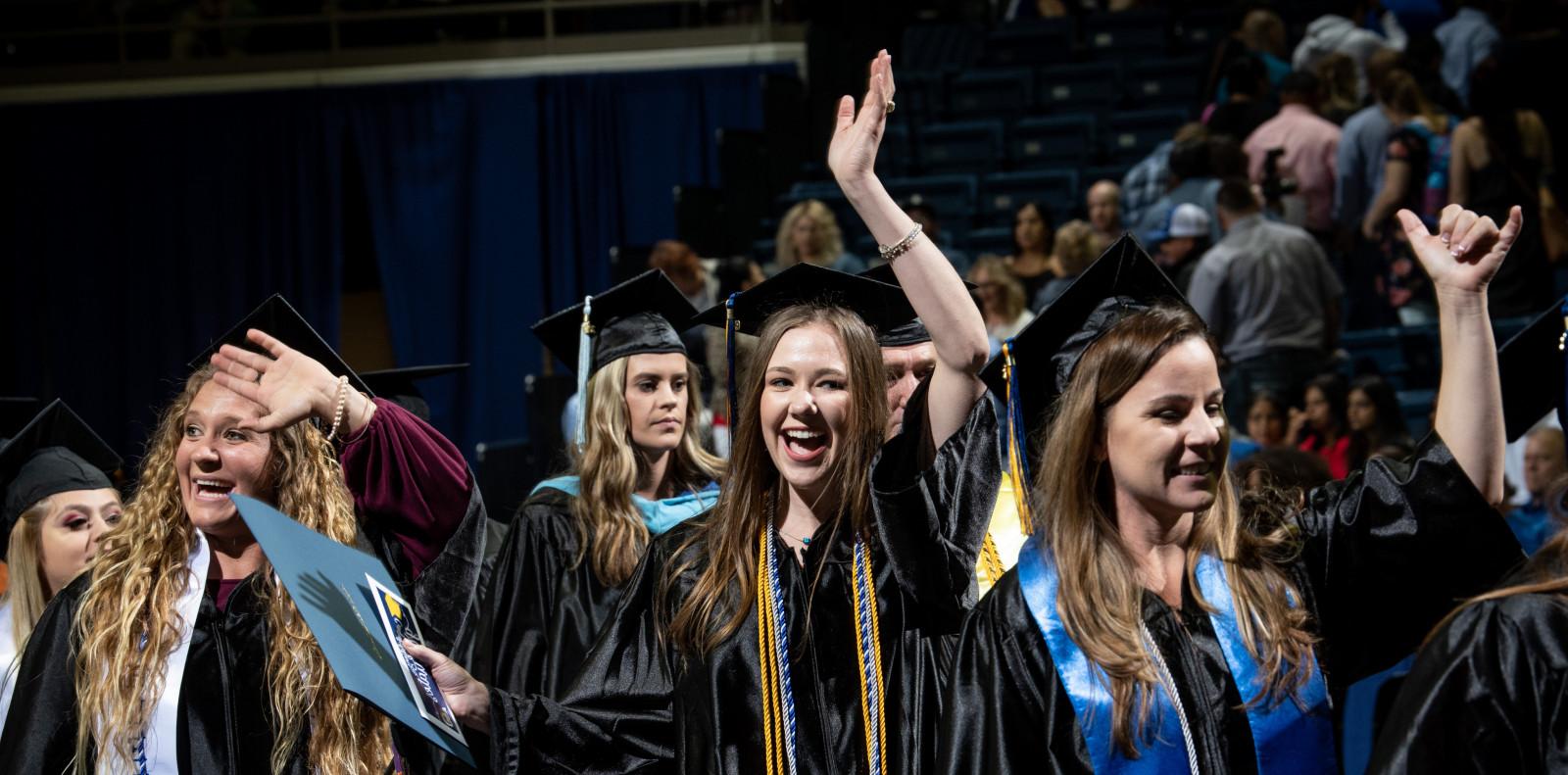 毕业生们在拿到文凭后挥手庆祝