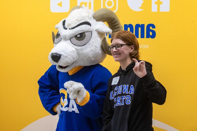 New student taking a picture with Roscoe, the mascot.